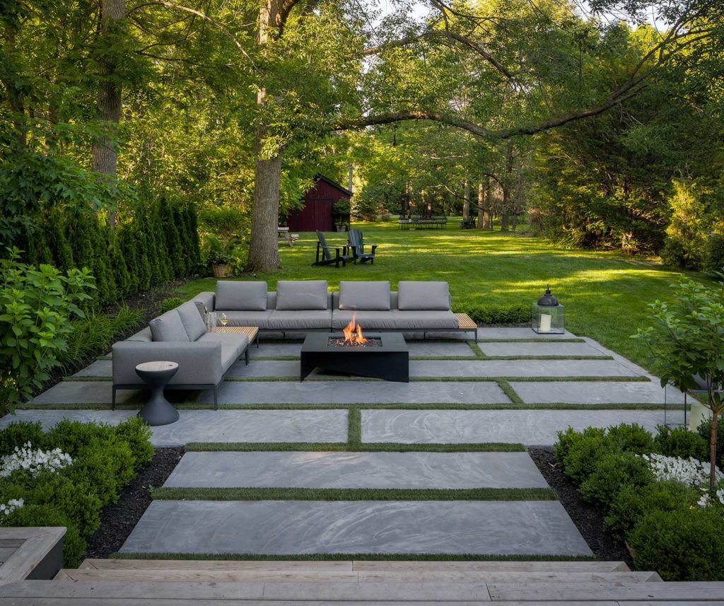 A patio with fire pit and seating area in the middle of it.