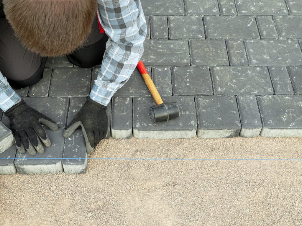 A person with gloves and hammer on the ground.